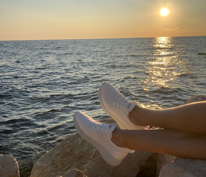 Dámské nohy ve volnočasové obuvi a moře